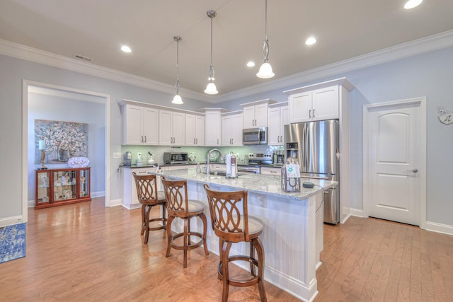 kitchen with sink, hanging light fixtures, an island with sink, stainless steel appliances, and white cabinets