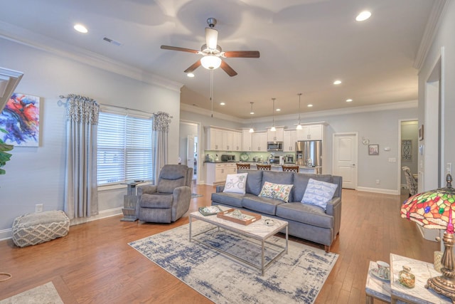 living room featuring ceiling fan, light wood-type flooring, and ornamental molding