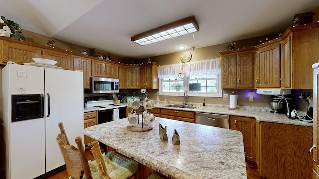 kitchen featuring appliances with stainless steel finishes, decorative light fixtures, a kitchen breakfast bar, a kitchen island, and sink