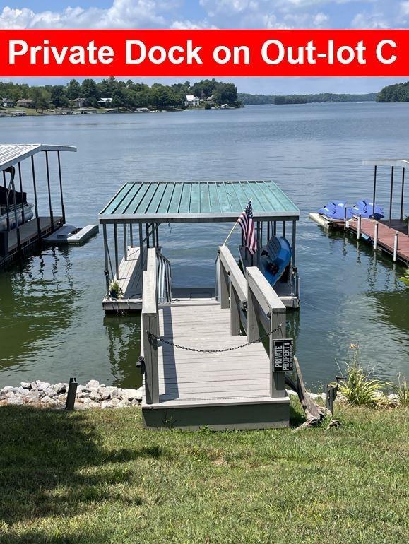 view of dock with a lawn and a water view