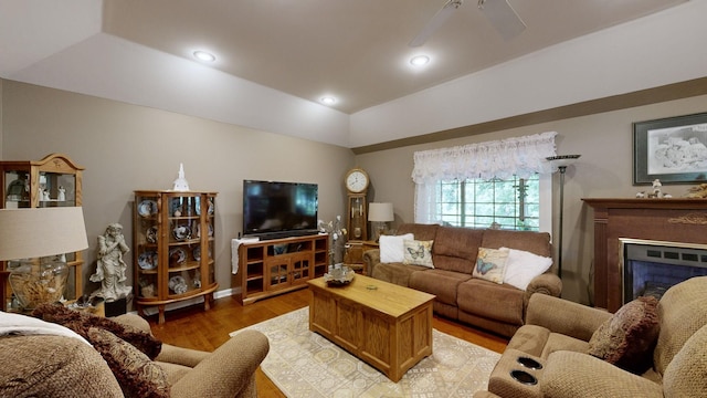 living room with ceiling fan, light hardwood / wood-style floors, and a raised ceiling