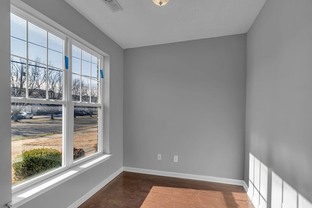 unfurnished room with a healthy amount of sunlight and dark hardwood / wood-style flooring