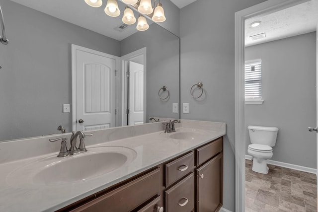 bathroom featuring toilet, vanity, an inviting chandelier, and a textured ceiling