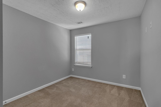 carpeted empty room featuring a textured ceiling