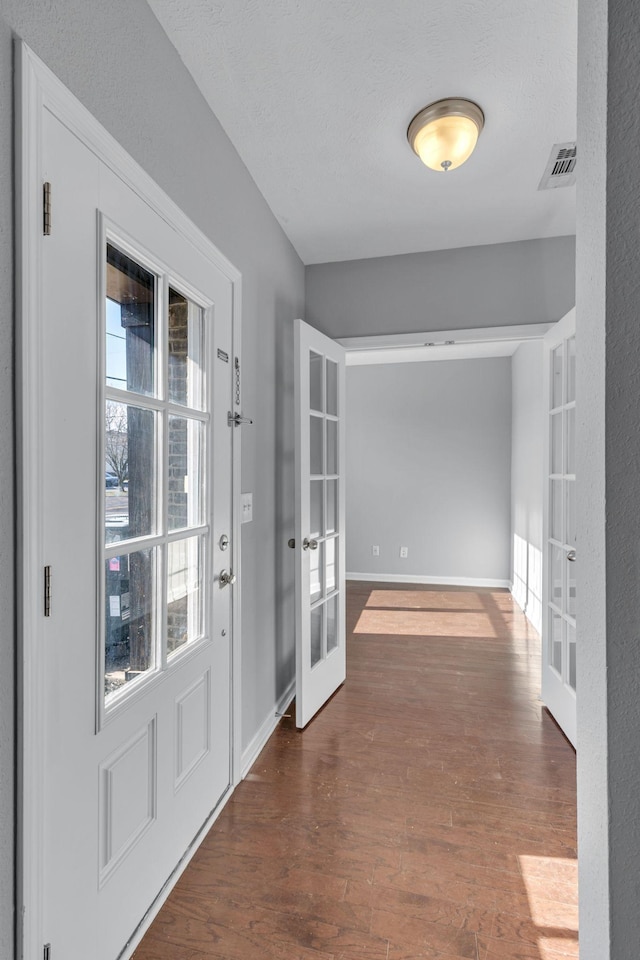 entryway featuring a textured ceiling, dark wood-type flooring, and french doors