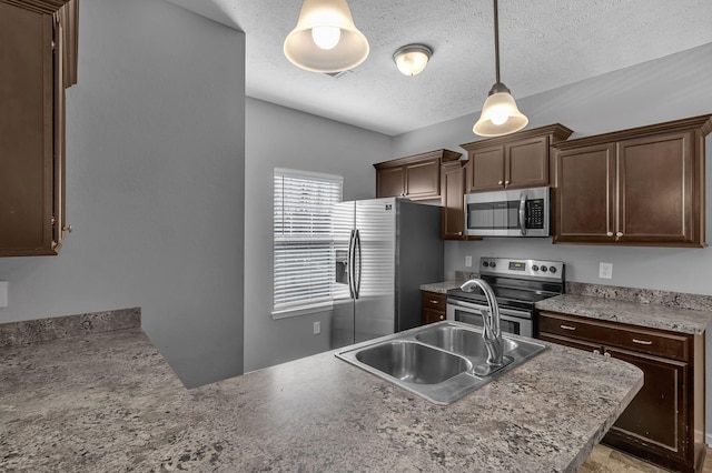 kitchen with sink, hanging light fixtures, appliances with stainless steel finishes, a textured ceiling, and dark brown cabinets