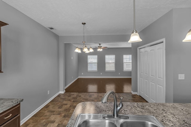 kitchen featuring a textured ceiling, sink, ceiling fan with notable chandelier, and decorative light fixtures