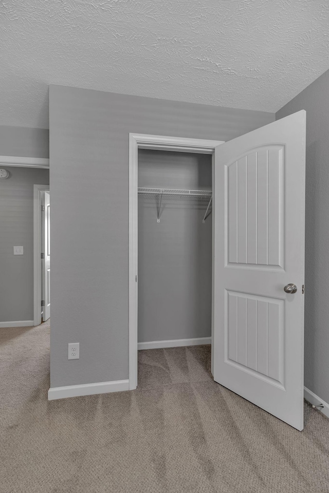 unfurnished bedroom with a textured ceiling, a closet, and carpet flooring