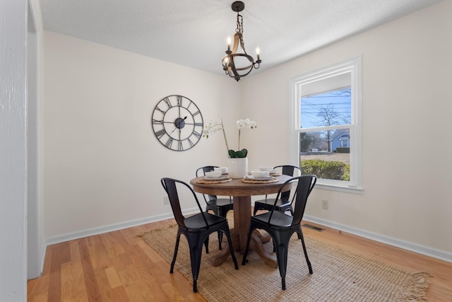 dining room with light wood-type flooring and a notable chandelier