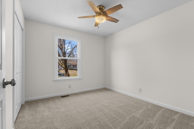 carpeted empty room featuring ceiling fan and a textured ceiling