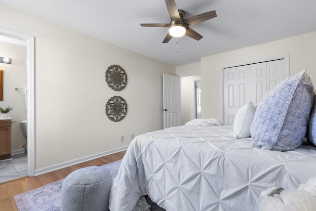 bedroom featuring ceiling fan, ensuite bath, a closet, wood-type flooring, and a textured ceiling