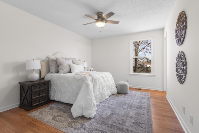 bedroom featuring ceiling fan, wood-type flooring, and a textured ceiling