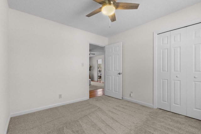 unfurnished bedroom with ceiling fan, a closet, and light carpet