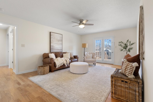 living room featuring a textured ceiling, ceiling fan, and light hardwood / wood-style floors