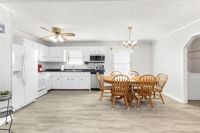 kitchen featuring washer / dryer, pendant lighting, sink, stainless steel appliances, and white cabinets