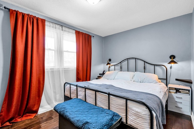 bedroom with a textured ceiling and dark wood-type flooring