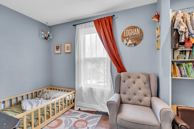 bedroom with a crib and hardwood / wood-style floors