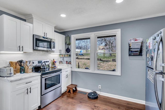 kitchen with light stone countertops, appliances with stainless steel finishes, tasteful backsplash, and white cabinetry