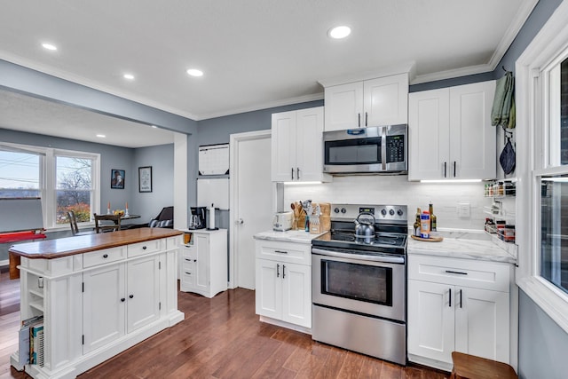 kitchen with tasteful backsplash, dark hardwood / wood-style floors, white cabinetry, stainless steel appliances, and light stone counters