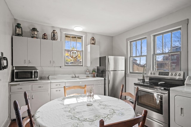 kitchen featuring white cabinets, washer / clothes dryer, sink, and stainless steel appliances