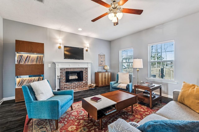 living room featuring a textured ceiling, ceiling fan, a fireplace, and dark hardwood / wood-style floors