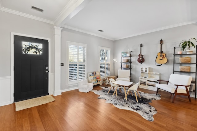 entryway featuring ornate columns, crown molding, and hardwood / wood-style floors