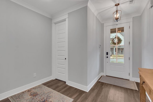 foyer entrance featuring dark hardwood / wood-style flooring, crown molding, and a chandelier