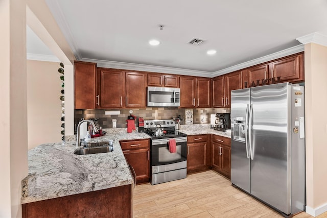 kitchen featuring appliances with stainless steel finishes, sink, backsplash, light wood-type flooring, and light stone counters