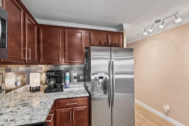 kitchen featuring light hardwood / wood-style floors, appliances with stainless steel finishes, decorative backsplash, ornamental molding, and light stone counters