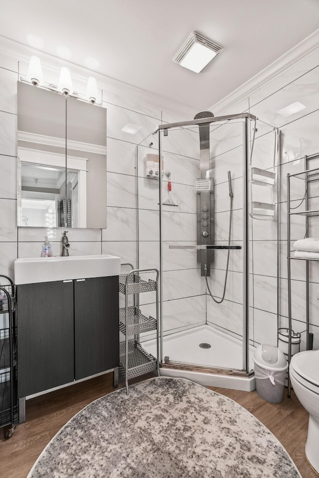 bathroom with an enclosed shower, vanity, crown molding, and hardwood / wood-style flooring