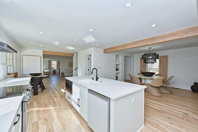 kitchen featuring a center island with sink, sink, white cabinetry, light wood-type flooring, and stainless steel appliances