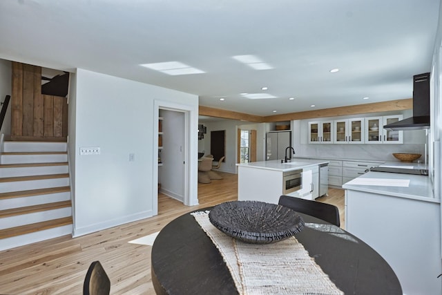 kitchen featuring light hardwood / wood-style floors, an island with sink, appliances with stainless steel finishes, white cabinets, and sink