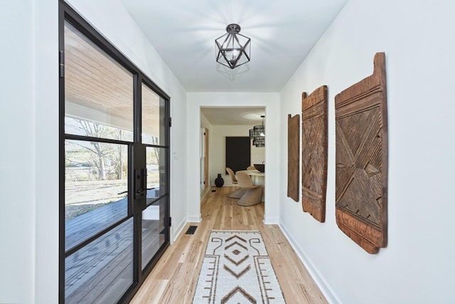 corridor featuring a notable chandelier and light hardwood / wood-style flooring