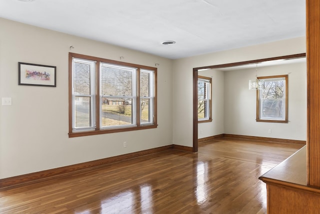 unfurnished room with a chandelier and dark hardwood / wood-style flooring