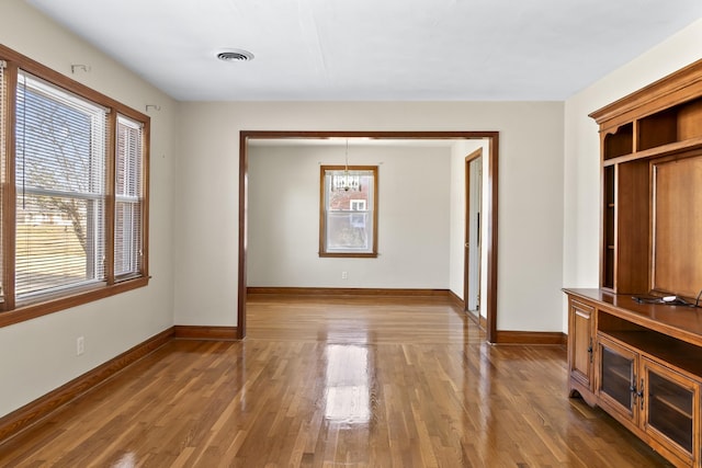 unfurnished room featuring an inviting chandelier and hardwood / wood-style floors