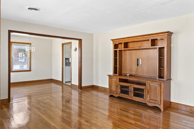 unfurnished living room featuring a notable chandelier and dark hardwood / wood-style floors