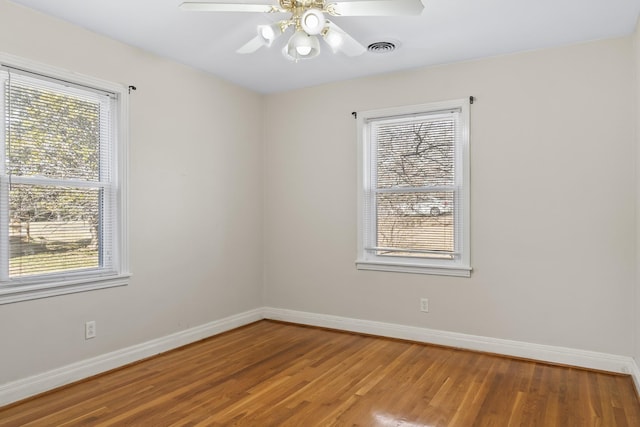 empty room featuring ceiling fan, wood-type flooring, and a healthy amount of sunlight