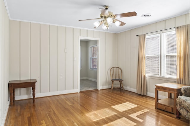 sitting room featuring wood-type flooring, ceiling fan, and crown molding