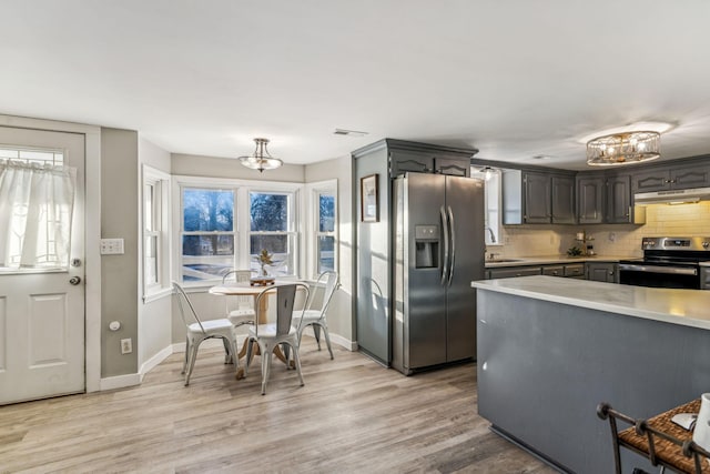 kitchen featuring backsplash, sink, light hardwood / wood-style flooring, appliances with stainless steel finishes, and a chandelier