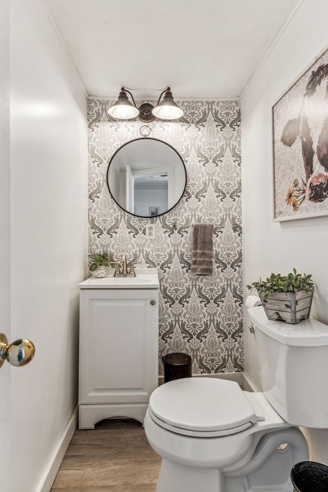 bathroom with toilet, vanity, ornamental molding, and hardwood / wood-style floors