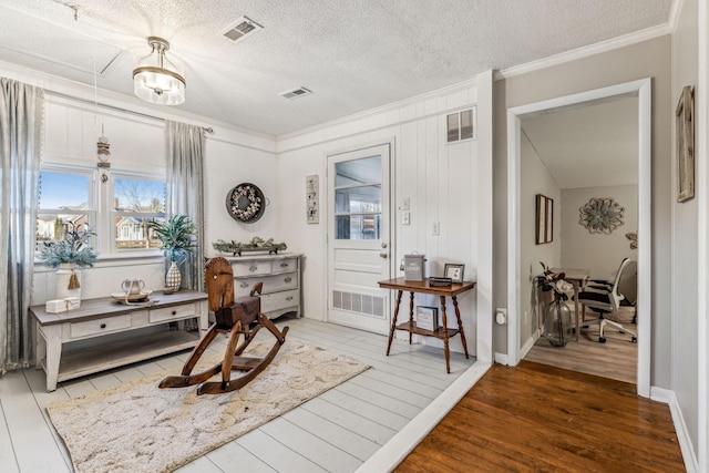 sitting room with ornamental molding, a textured ceiling, and hardwood / wood-style floors