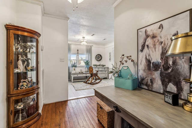 entryway with wood-type flooring, crown molding, and a textured ceiling