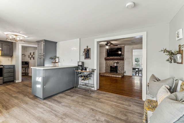 kitchen with ceiling fan, gray cabinets, kitchen peninsula, decorative backsplash, and wood-type flooring