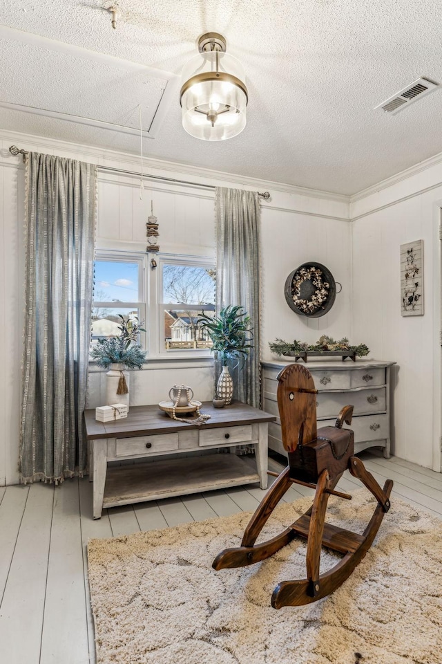 living area with a textured ceiling, ornamental molding, and light tile patterned flooring