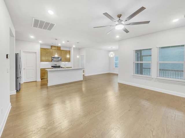 unfurnished living room with ceiling fan, sink, and light hardwood / wood-style floors