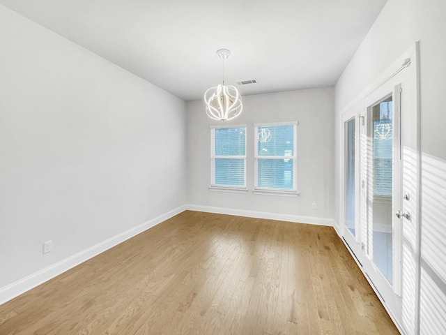 empty room featuring light wood-type flooring and an inviting chandelier