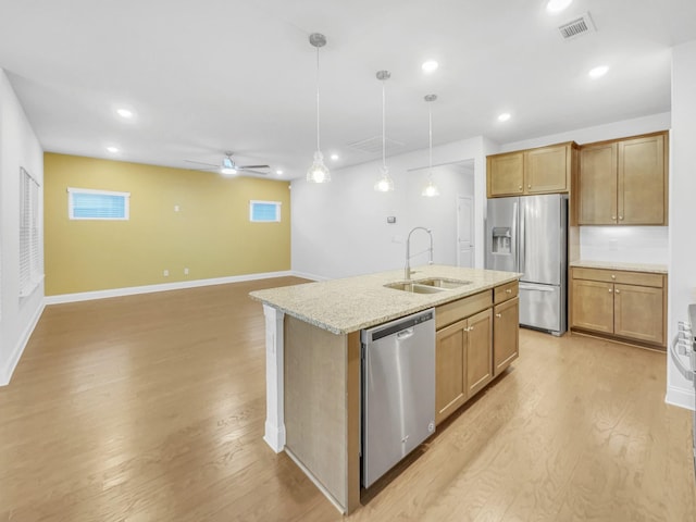 kitchen featuring sink, pendant lighting, stainless steel appliances, and an island with sink