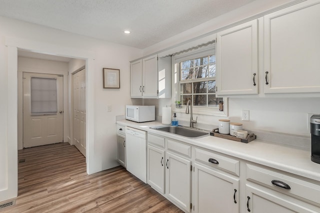 kitchen featuring a textured ceiling, white cabinetry, sink, and white appliances