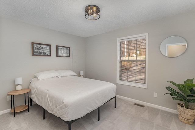 bedroom with light colored carpet and a textured ceiling