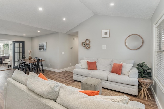 living room with a textured ceiling, light hardwood / wood-style flooring, and lofted ceiling